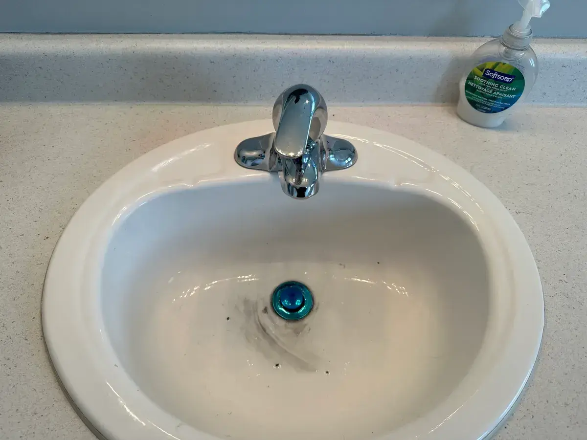 Polished chrome centerset faucet installed on a white bathroom sink