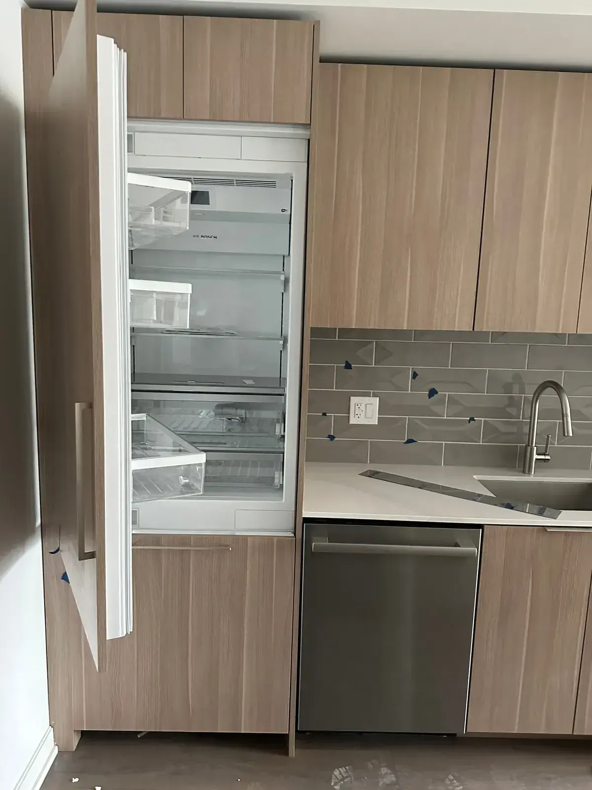 Refrigerator installed with door open in wood cabinetry