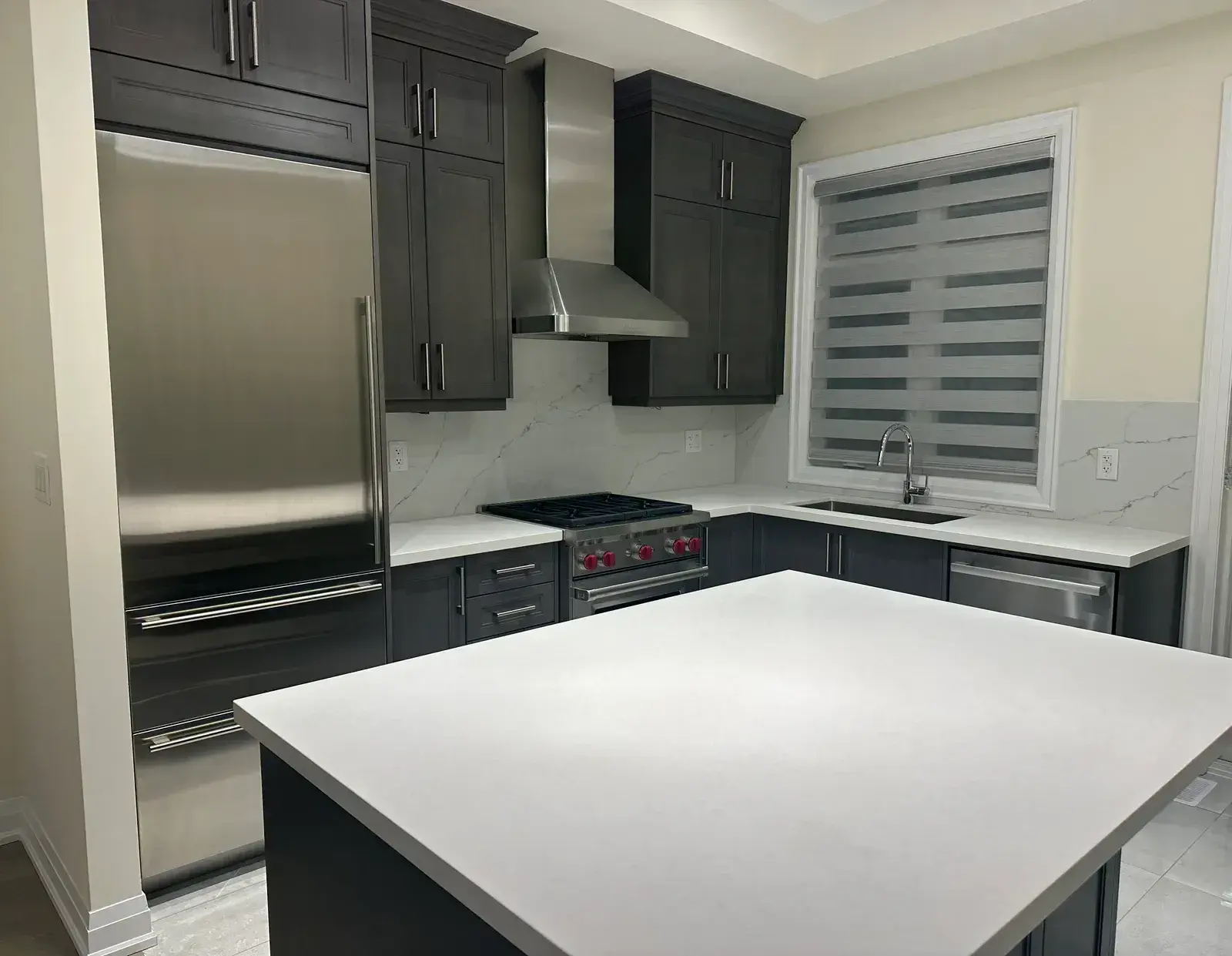 Second angle of the finished kitchen: built-in refrigerator, Wolf range and chimney hood around a white quartz island