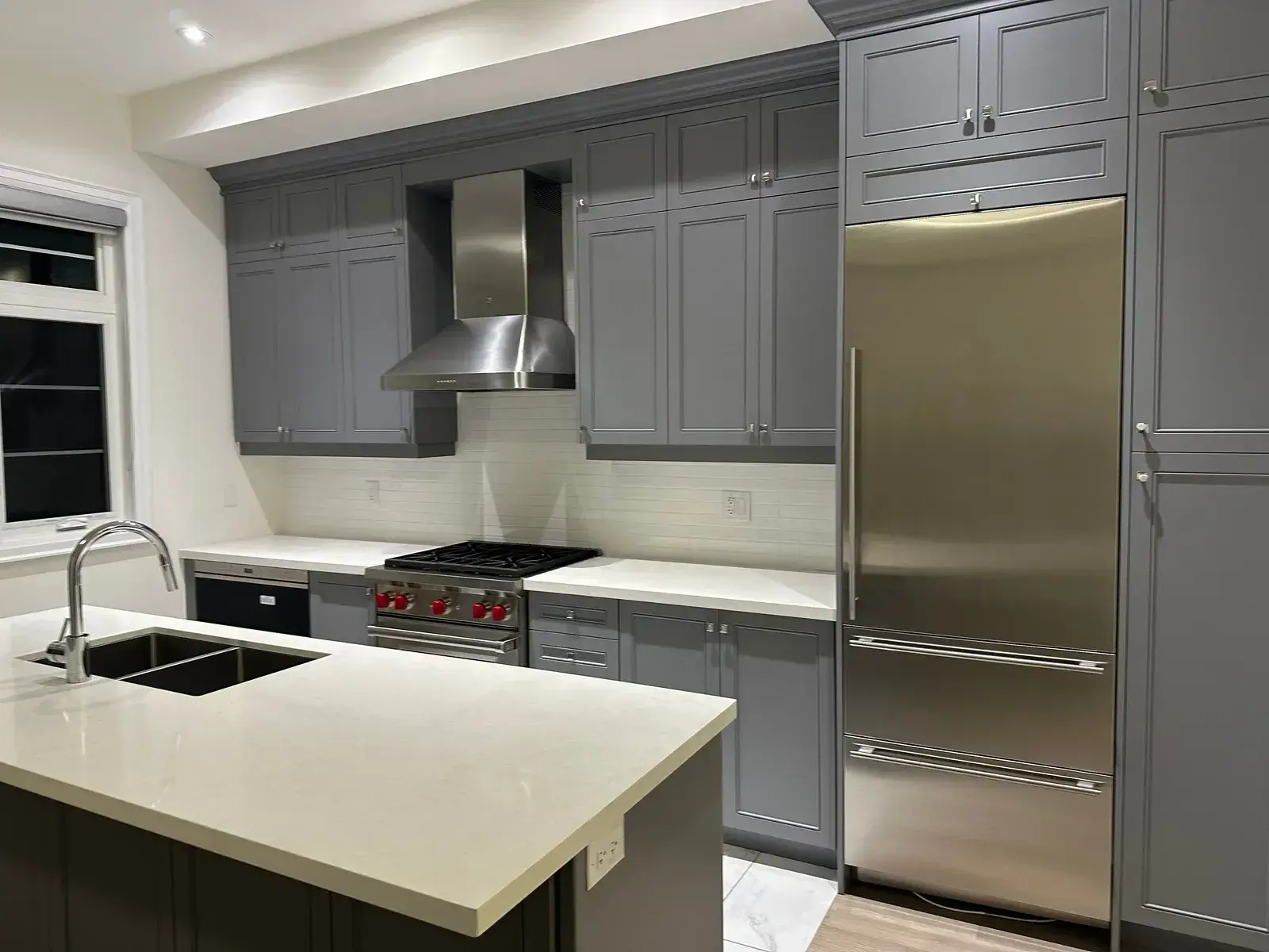 Grey kitchen with Wolf rangetop, chimney hood and panel-ready fridge