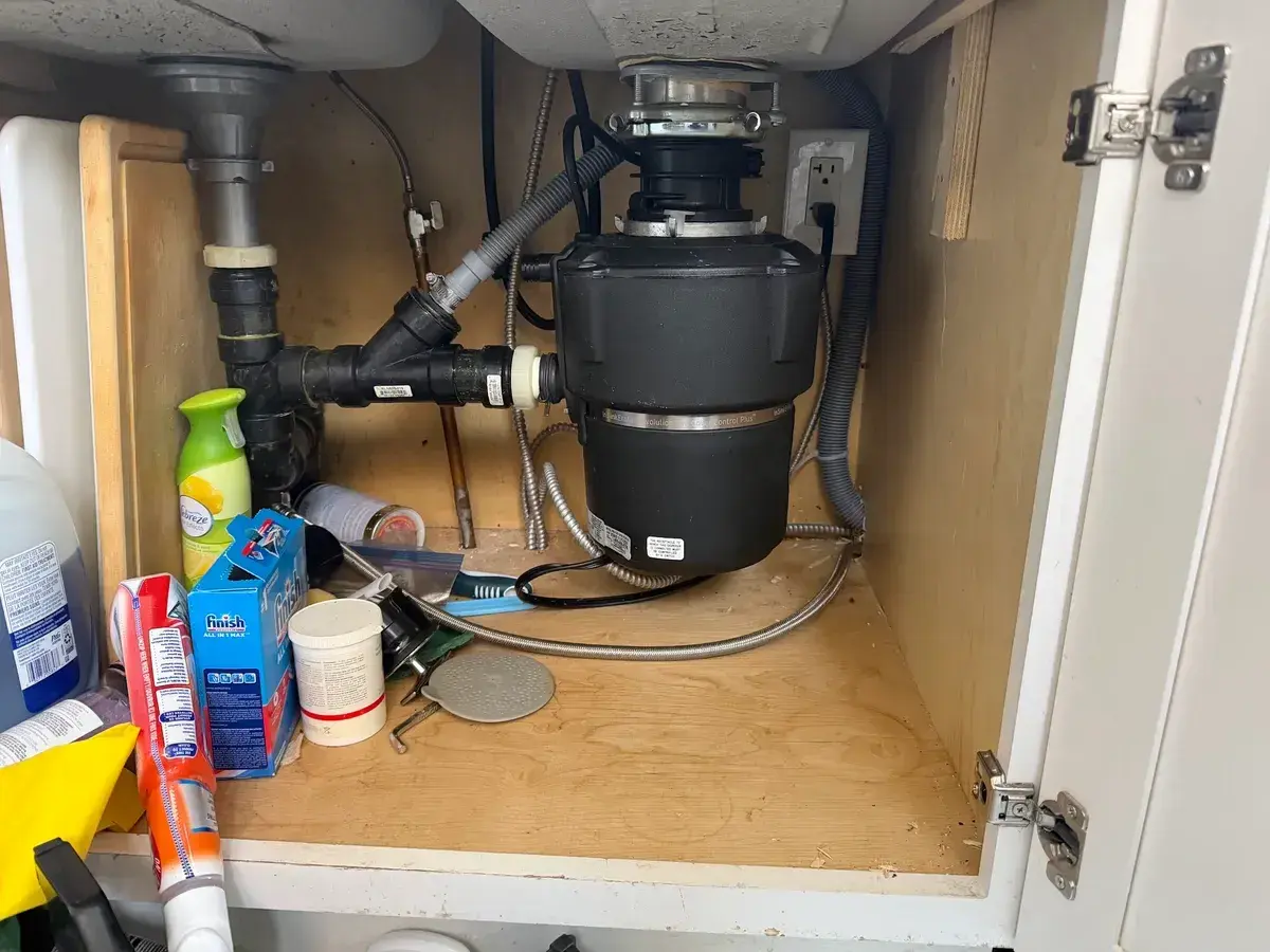 New pipework and garbage disposal installed under a kitchen sink